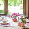 Holztisch in Altbauwohnung mit Blumen und Tischsets aus Leder in Lavendelfarbe